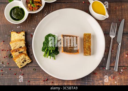 Gebratenes Lachsfilet mit verwelktem Spinat und Kartoffelkrokette Stockfoto