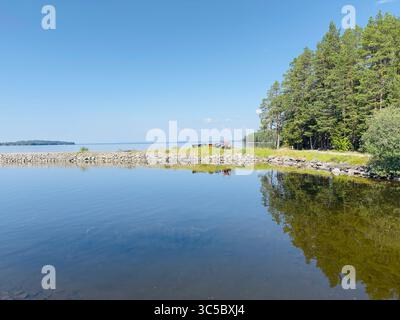 Ein atemberaubender Blick auf einen ruhigen See, perfektes Wetter, das den lebhaften blauen Himmel und die üppigen Bäume reflektiert. Stockfoto