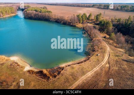 Lakeshore im Herbst. Blick von oben auf den kleinen See und die unbefestigte Straße. Naturlandschaft. Naturhintergrund Stockfoto
