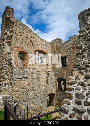 Ruinen der mittelalterlichen Burg Cimburk in der Tschechischen Republik, mit bogenförmigen und hölzernen verstärkten Fenstern, verwittertem Mauerwerk und blauem Himmel mit Stockfoto