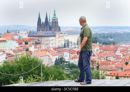 Reife Touristen posieren stolz über den roten Dächern von Prag, mit der berühmten Kathedrale dahinter Stockfoto