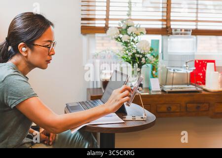 Geschäftsfrau Hand mit Handy und Laptop auf Tisch. Stockfoto