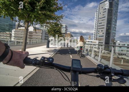 Radfahren über die Moreelse brug, Fußgänger- und Radfahrerbrücke über die Gleise von Utrecht Centraal, Hauptbahnhof, Rabobank Stockfoto