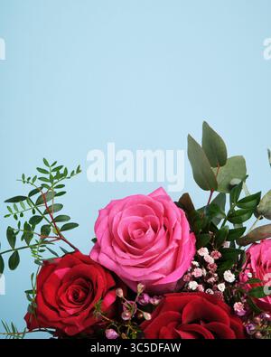 Banner mit einem Blumenstrauß aus rosa und roten Rosen auf hellblauem Hintergrund. Kopierraum. Stockfoto