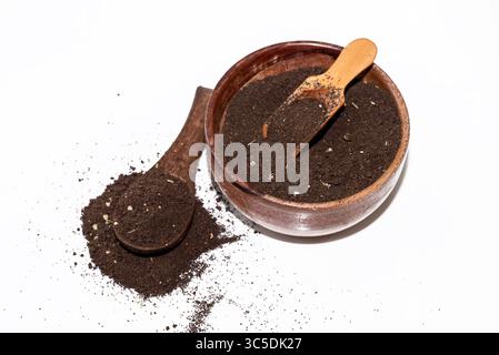 Schwarzes Teepulver im hölzernen Löffel isoliert auf weißem Hintergrund. Teepulver Teeblatt nach dem Mischen und Trocknen in einer hölzernen Schüssel Stockfoto