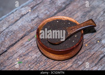 indischer schwarzer Tee, Teelöffel mit Teeblättern auf Holztisch. Schwarzes Teepulver auf hölzernem Hintergrund. Nahaufnahme Stockfoto