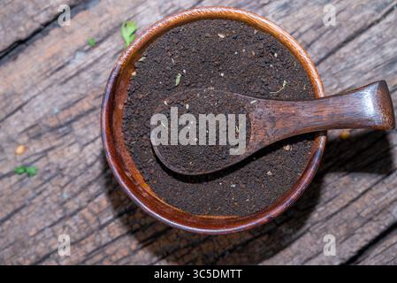 indischer schwarzer Tee, Teelöffel mit Teeblättern auf Holztisch. Schwarzes Teepulver auf hölzernem Hintergrund. Nahaufnahme Stockfoto