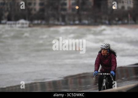 5. Februar 2020, USA: Ein Radfahrer fährt am Dienstag, 4. Februar 2020, auf dem Lakefront Trail in der Nähe des Strandes North Avenue in Chicago, während die Wellen am Ufer des Sees abstürzen. (Kreditbild: © TNS via ZUMA Wire) Stockfoto
