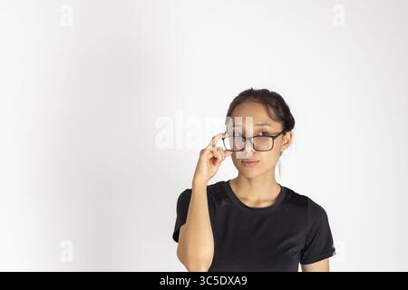 Eine junge Frau mit dunklen Haaren, die ein schwarzes T-Shirt und eine Brille trägt, sucht nach Stockfoto