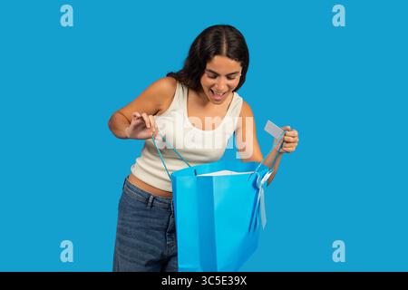 Frau, die eifrig in eine große blaue Einkaufstasche schaut Stockfoto