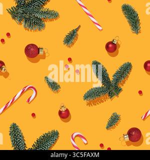 Nahtloses Weihnachtsmuster mit Tannenzweigen, Kugeln und Zuckerrohr auf gelbem Hintergrund Stockfoto