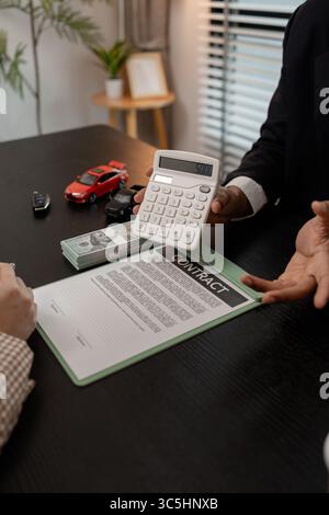 Ein Autoverkäufer erklärt die Details eines Autos und den Preis, an dem ein Käufer interessiert ist, der Verkaufsleiter des Verkaufsraums erläutert die Menge an Int. Stockfoto