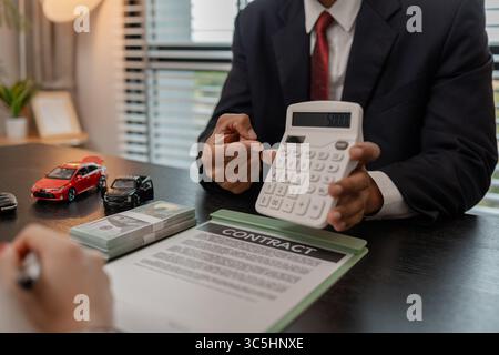 Ein Autoverkäufer erklärt die Details eines Autos und den Preis, an dem ein Käufer interessiert ist, der Verkaufsleiter des Verkaufsraums erläutert die Menge an Int. Stockfoto