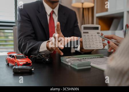 Ein Autoverkäufer erklärt die Details eines Autos und den Preis, an dem ein Käufer interessiert ist, der Verkaufsleiter des Verkaufsraums erläutert die Menge an Int. Stockfoto