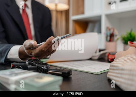 Ein Autoverkäufer erklärt die Details eines Autos und den Preis, an dem ein Käufer interessiert ist, der Verkaufsleiter des Verkaufsraums erläutert die Menge an Int. Stockfoto