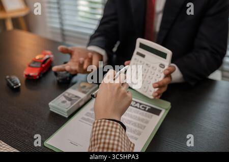 Ein Autoverkäufer erklärt die Details eines Autos und den Preis, an dem ein Käufer interessiert ist, der Verkaufsleiter des Verkaufsraums erläutert die Menge an Int. Stockfoto