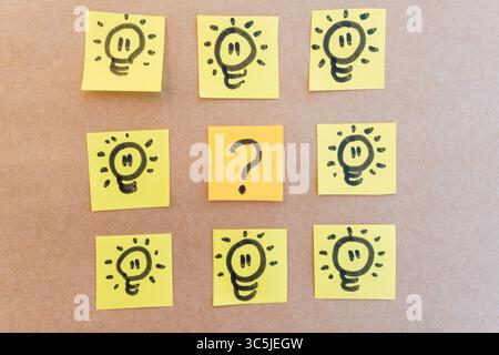 Fragezeichen umgeben von beleuchteten Spots, gezeichnet auf farbigem Papier mit schwarzem Marker mit einheitlichem, solidem Hintergrund Stockfoto