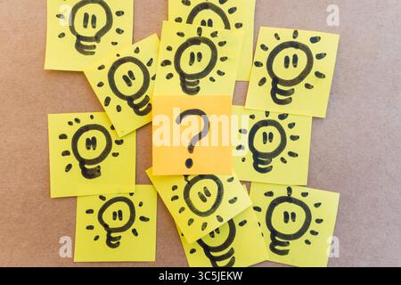 Fragezeichen umgeben von beleuchteten Spots, gezeichnet auf farbigem Papier mit schwarzem Marker mit einheitlichem, solidem Hintergrund Stockfoto