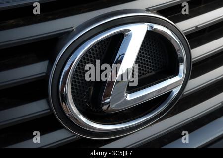 Nahaufnahme eines Lexus-Emblems auf einem dunklen Kühlergrill, das das Chrom-L in einem Oval mit Mesh-Hintergrund zeigt. Stockfoto
