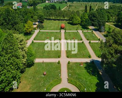Aus der Vogelperspektive auf gepflegte Rasenflächen und geometrisch angeordnete Wege bilden einen symmetrischen Wandteppich, der mit künstlerischen Skulpturen im Park in Valkenburg, Limburg, Niederlande, gespickt ist. Stockfoto