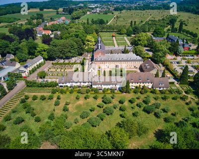 Blick aus der Vogelperspektive auf einen ruhigen Klosterkomplex mit gepflegten Gärten und einem historischen Friedhof inmitten üppiger Vegetation, Valkenburg, Limburg, Niederlande. Stockfoto