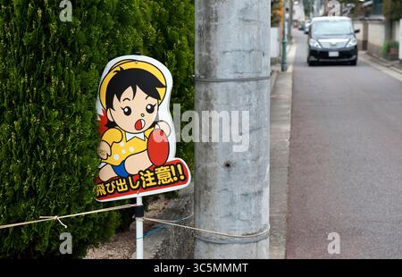 Ein animiertes Warnschild, das in ganz Japan auf den Straßen der Nachbarschaft zu sehen ist, sagt: "Tobidashi Chui" (Vorsicht, fliegende Kinder), also langsam, Vorsicht und Vorsicht. Stockfoto