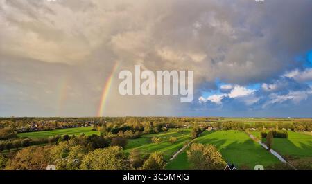 Atemberaubender Balkonblick auf einen Regenbogen über Purmerends Landschaft bei einem stürmischen Sommeruntergang in der Nähe von Amsterdam, Niederlande Stockfoto