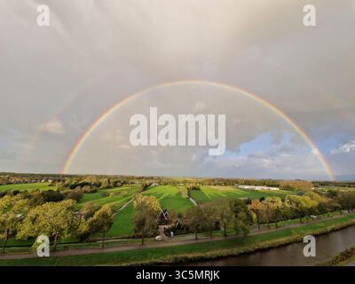 Atemberaubender Balkonblick auf einen Regenbogen über Purmerends Landschaft bei einem stürmischen Sommeruntergang in der Nähe von Amsterdam, Niederlande Stockfoto
