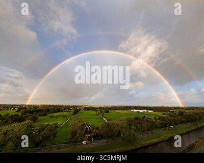 Atemberaubender Balkonblick auf einen Regenbogen über Purmerends Landschaft bei einem stürmischen Sommeruntergang in der Nähe von Amsterdam, Niederlande Stockfoto