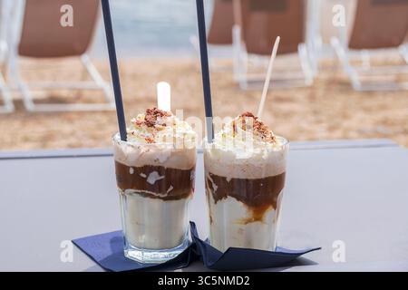 Zwei Gläser Eiskaffee mit Sahne und Schokolade am Strand. Stockfoto