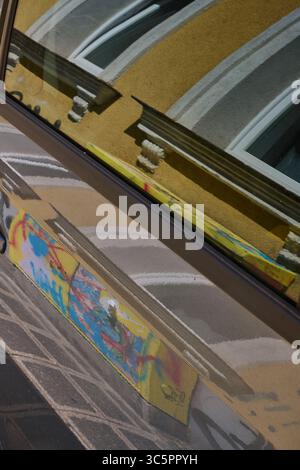 Fassadendetails spiegeln sich in einem parkenden Auto wider Stockfoto