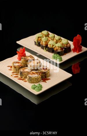 Sushi auf schwarzem Hintergrund. Sushi-Brötchen mit Lachs, Kaviar, Gurke, Frischkäse, Nori, sesamsamen. Stockfoto