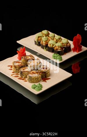 Sushi auf schwarzem Hintergrund. Sushi-Brötchen mit Lachs, Kaviar, Gurke, Frischkäse, Nori, sesamsamen. Stockfoto