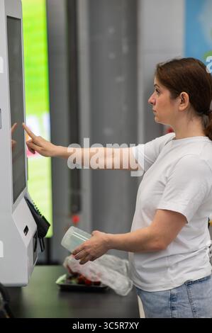 Eine Frau scannt Artikel an einer Selbstkasse. Stockfoto