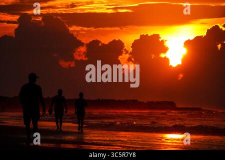 Isle Of Palms, Usa. 30. Juli 2025. Strandbesucher werden vom Sonnenaufgang umrahmt, während sich Sturmwolken in das Low Country ziehen, am 30. Juli 2025 in Isle of Palms, South Carolina. Gewitter sorgten nach einer Woche mit Temperaturen über 100 Grad an der Küste für vorübergehende Entspannung. Quelle: Richard Ellis/Richard Ellis/Alamy Live News Stockfoto