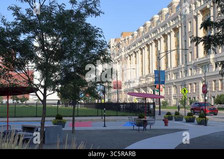 07 24 2025 Chicago IL: Außen-Tür-Sitzbereich durch ein großes pristigisches Gebäude mit Sonnenschirmen, Bäumen und Pflanzen Stockfoto