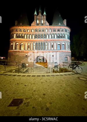 Das berühmte Holstentor in Lübeck, Deutschland, ist bei Nacht wunderschön beleuchtet und zeigt die mittelalterliche Architektur des historischen Stadttors. Stockfoto