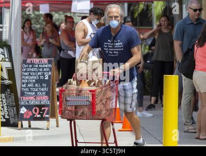 31. März 2020, Miami, FL, USA: Lebensmitteleinkäufer stehen vor dem Laden und verlassen am Dienstag, den 31. März 2020, mit Gesichtsmasken bei Trader Joe';s in Miami. (Kreditbild: © TNS via ZUMA Wire) Stockfoto