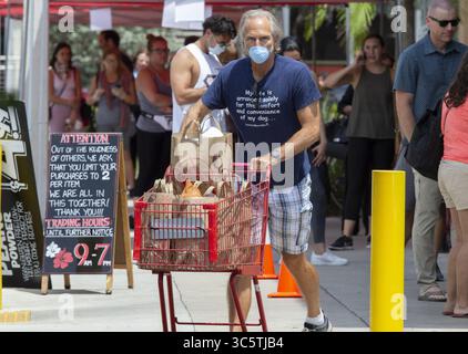 31. März 2020, Miami, FL, USA: Lebensmitteleinkäufer stehen vor dem Laden und verlassen am Dienstag, den 31. März 2020, mit Gesichtsmasken im Trader Joe's at in Miami. (Kreditbild: © TNS via ZUMA Wire) Stockfoto