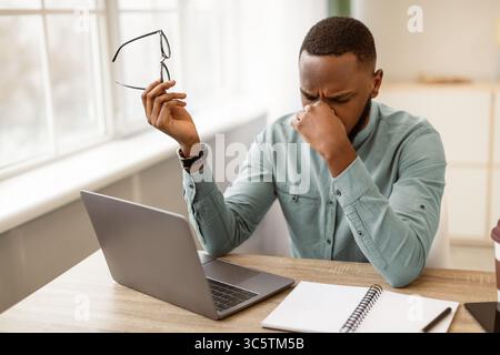 Müde Afrikanische Geschäftsmann Holding Brillen Massieren Nasenbrücke Im Büro Stockfoto