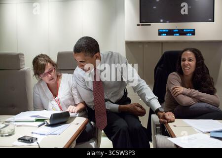 11. Juli 2009 - Air Force One, USA - US-Präsident BARACK OBAMA sitzt auf dem Arm des stellvertretenden Stabschefs des Weißen Hauses, ALYSSA MASTROMONACO, und geht die Papiere durch, während MONA SUPHEN in der Nähe der Air Force One sitzt. Das Präsidentenflugzeug ist auf dem Rückweg aus Ghana. (Kreditbild: © Pete Souza/das Weiße Haus/ZUMAPRESS.com) Stockfoto