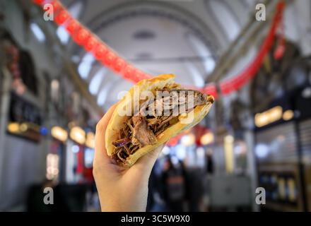 Eine Frauenhand hält einen frischen Döner im Inneren des Großen Basars in Istanbul, Türkei, eine perfekte Idee für kulinarische Reisen und die Erkundung der lokalen Küche Stockfoto