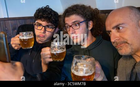 Prag, Tschechische Republik, 5. August 2023. Gruppenselfie mit zwei jungen Leuten und einem Mann mittleren Alters, der eine Tasse Bier trinkt. Lifestyle, gemeinsam trinken Stockfoto