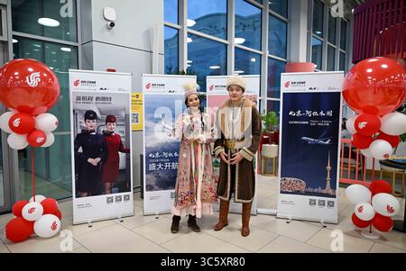 Almaty, Kasachstan. 30. Juli 2025. Menschen in traditioneller kasachischer Tracht stehen am 30. Juli 2025 auf dem Almaty International Airport in Almaty, Kasachstan, vor Plakaten der neuen Flugstrecke zwischen Peking und Almaty. Die chinesische Fluggesellschaft Air China startete am Mittwoch eine direkte Flugreise zwischen Peking und Almaty, Kasachstan, mit einer Zeremonie am Almaty International Airport für den Erstflug. Quelle: Li Renzi/Xinhua/Alamy Live News Stockfoto