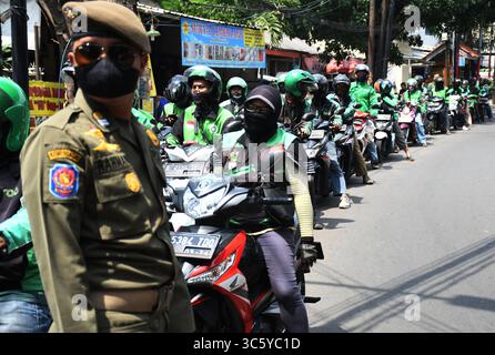5. September 2019, Cipayung, Jakarta, Indonesien: Online-Motorradfahrer stehen bereit, am 18. April 2020 Lebensmittel von Freiwilligen in der Gegend von Cipayung, Jakarta, zu kaufen. 200 Lebensmittelpakete wurden online an Motorradtaxifahrer verteilt, weil ihr Einkommen seit der Co-Pandemie in Indonesien zurückging. Von den vorherigen vielen Bestellungen für den Transport verwenden die Benutzer jetzt Fahrer, um Lebensmittel zu bestellen, für den täglichen Bedarf einzukaufen oder Waren zu liefern. (Bild: © Dasril Roszandi/ZUMA Wire) Stockfoto
