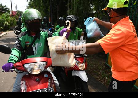 5. September 2019, Cipayung, Jakarta, Indonesien: Freiwillige geben am 18. April 2020 Lebensmittelpakete an Online-Motorradfahrer in der Region Cipayung, Jakarta. 200 Lebensmittelpakete wurden online an Motorradtaxifahrer verteilt, weil ihr Einkommen seit der Co-Pandemie in Indonesien zurückging. Von den vorherigen vielen Bestellungen für den Transport verwenden die Benutzer jetzt Fahrer, um Lebensmittel zu bestellen, für den täglichen Bedarf einzukaufen oder Waren zu liefern. (Bild: © Dasril Roszandi/ZUMA Wire) Stockfoto