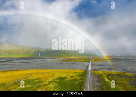 Blick aus der Vogelperspektive auf die Islandstraße mit Regenbogen und Wasserfällen Stockfoto