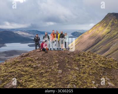 Gruppe von Menschen auf moosbedecktem Hügel mit Blick auf den See in Island Stockfoto