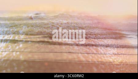 Sanfte Meereswellen reflektieren den pastellfarbenen Himmel bei Sonnenuntergang am Sandstrand mit Sonnenstrahlen Stockfoto