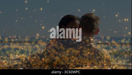 Lächelnde Frau umarmt Mann auf dem Deck am Wasser, mit Metallgeländern und goldenen Bokeh-Lichtern Stockfoto